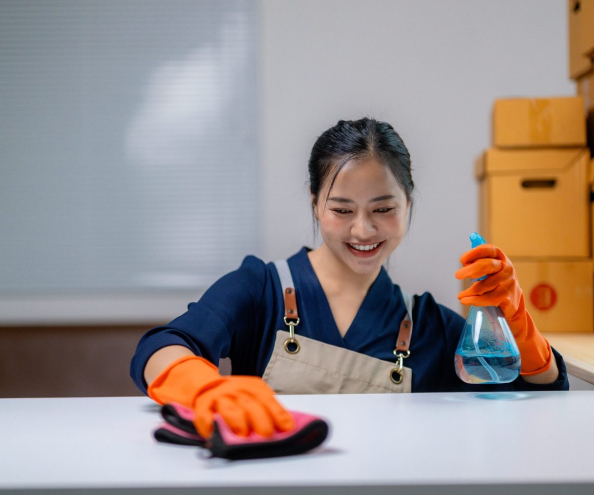 Smiling cleaner using spray and cloth on a white table